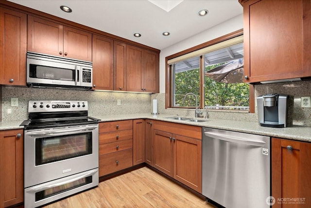 9 199th Pl SE, Bothell, WA 98012 - kitchen with stainless steel appliances, a sink, light wood finished floors, brown cabinets, and backsplash