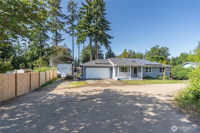 7606 Illahee Rd NE, Bremerton, WA 98311 - ranch-style house featuring a carport, dirt driveway, a porch, an attached garage, and roof mounted solar panels