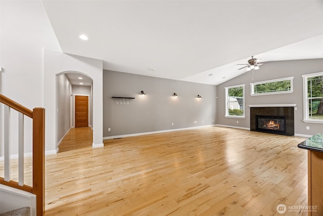 13123 320th Street Ct E, Graham, WA 98338 - unfurnished living room with ceiling fan, light wood-style flooring, vaulted ceiling, healthy amount of natural light, and arched walkways
