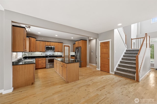 13123 320th Street Ct E, Graham, WA 98338 - kitchen featuring appliances with stainless steel finishes, a sink, light wood-style flooring, backsplash, and a kitchen island