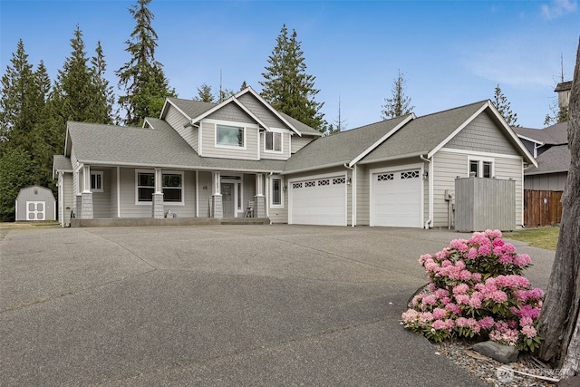 13123 320th Street Ct E, Graham, WA 98338 - view of front of house with a garage, a porch, asphalt driveway, a storage unit, and roof with shingles