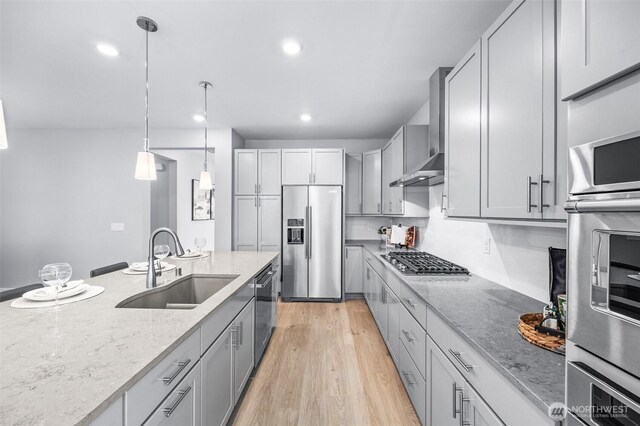 29215 217th Ct SE, Black Diamond, WA 98010 - kitchen with appliances with stainless steel finishes, a sink, wall chimney range hood, light stone counters, and light wood-style flooring