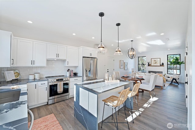3906 Crosswinds Ct, Anacortes, WA 98221 - kitchen featuring stainless steel appliances, a kitchen bar, wood finished floors, white cabinets, and backsplash