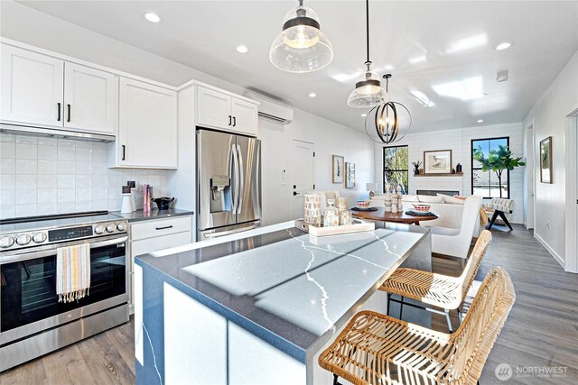3906 Crosswinds Ct, Anacortes, WA 98221 - kitchen featuring stainless steel appliances, an AC wall unit, light wood-style floors, tasteful backsplash, and white cabinetry
