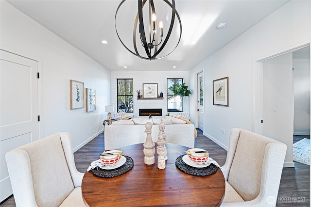 3906 Crosswinds Ct, Anacortes, WA 98221 - dining area featuring dark wood-style flooring, a chandelier, recessed lighting, a lit fireplace, and baseboards