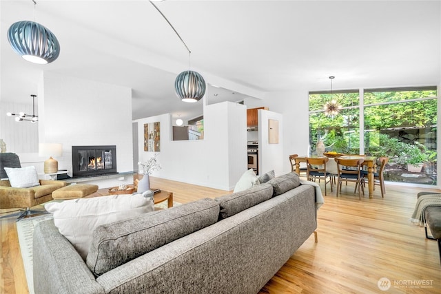 5 Wembley Ln, Mercer Island, WA 98040 - living area featuring light wood finished floors, a chandelier, a glass covered fireplace, and a wall of windows