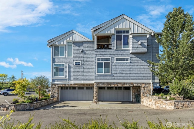 656 Daley St Unit 102, Edmonds, WA 98020 - view of front facade with board and batten siding, concrete driveway, a garage, and stone siding