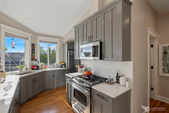 656 Daley St Unit 102, Edmonds, WA 98020 - kitchen with appliances with stainless steel finishes, gray cabinetry, a sink, lofted ceiling, and tasteful backsplash
