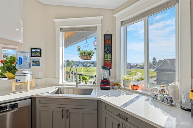 656 Daley St Unit 102, Edmonds, WA 98020 - kitchen with stainless steel dishwasher, gray cabinetry, vaulted ceiling, a sink, and light stone counters