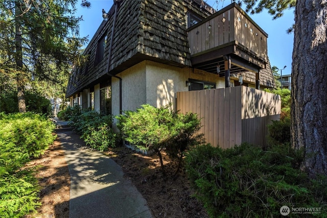 8627 25th Ave SW Unit B, Seattle, WA 98106 - view of side of home with mansard roof, stucco siding, and a balcony