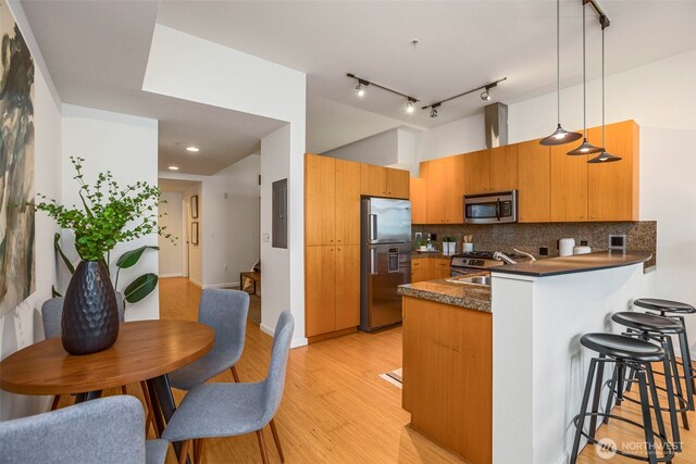 17 W Mercer St Unit 218, Seattle, WA 98119 - kitchen featuring appliances with stainless steel finishes, a peninsula, dark countertops, a kitchen breakfast bar, and decorative backsplash