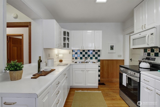 2433 E Valley St, Seattle, WA 98112 - kitchen with electric range, white microwave, a sink, glass insert cabinets, and backsplash