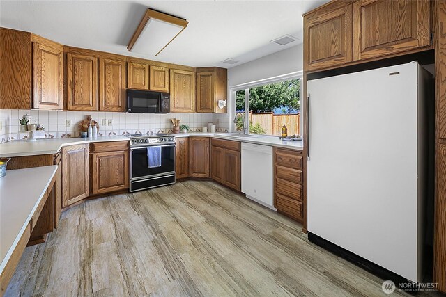 14210 NE 63rd Ct, Redmond, WA 98052 - kitchen featuring white appliances, brown cabinetry, light wood-type flooring, and backsplash