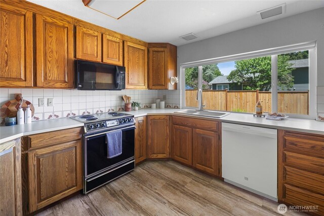 14210 NE 63rd Ct, Redmond, WA 98052 - kitchen with black microwave, white dishwasher, range with electric stovetop, a sink, and backsplash