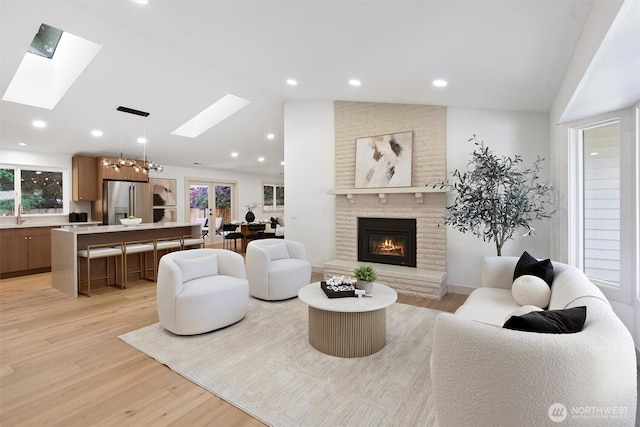 7118 177th St SW, Edmonds, WA 98026 - living room featuring a skylight, lofted ceiling, light wood finished floors, a brick fireplace, and a chandelier