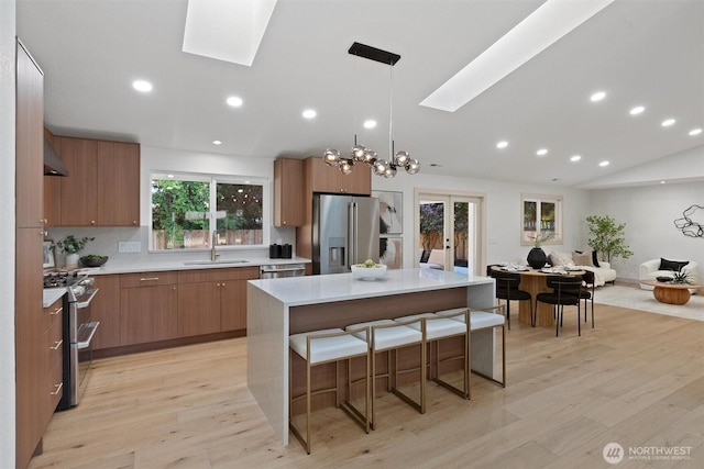 7118 177th St SW, Edmonds, WA 98026 - kitchen featuring appliances with stainless steel finishes, a skylight, a sink, light wood-type flooring, and vaulted ceiling