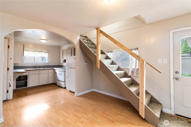 611 NE Pioneer, Castle Rock, WA 98611 - kitchen featuring arched walkways, white appliances, light wood finished floors, and baseboards