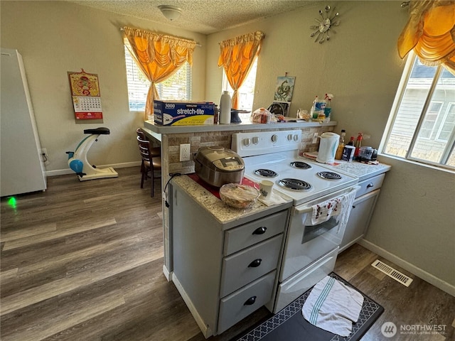 720 S 37th St, Tacoma, WA 98418 - kitchen featuring white electric range, a textured ceiling, dark wood-style floors, a peninsula, and baseboards