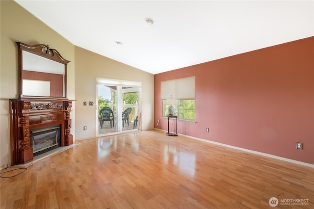5419 N Court St, Ruston, WA 98407 - unfurnished living room featuring lofted ceiling, light wood-type flooring, a glass covered fireplace, and baseboards