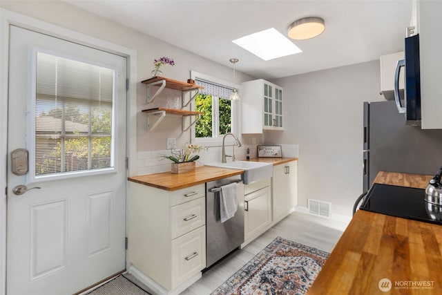 19027 37th Ave S, Seatac, WA 98188 - kitchen featuring butcher block counters, appliances with stainless steel finishes, a skylight, a sink, and decorative backsplash