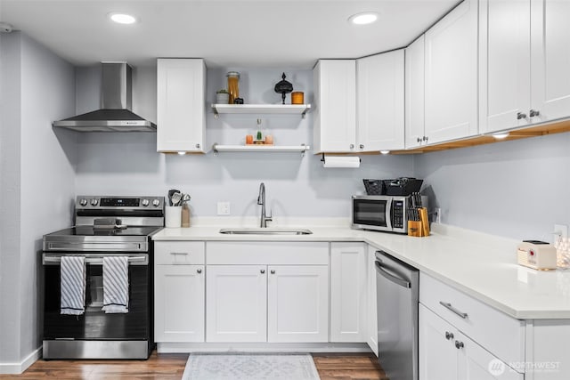 140 Tremont St, Port Orchard, WA 98366 - kitchen with wall chimney range hood, stainless steel appliances, a sink, wood finished floors, and white cabinets