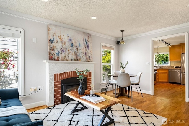 7530 25th Ave NW, Seattle, WA 98117 - living room featuring crown molding, healthy amount of natural light, a textured ceiling, light wood finished floors, and a fireplace