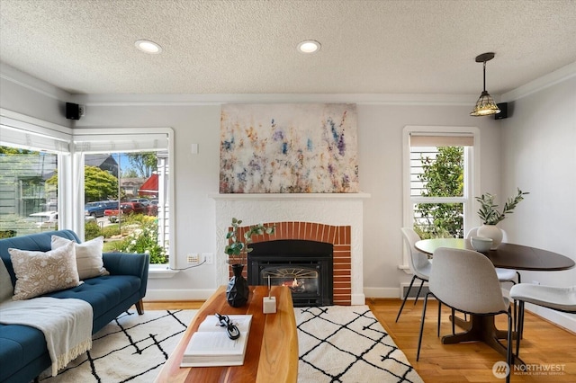 7530 25th Ave NW, Seattle, WA 98117 - living area with crown molding, a textured ceiling, light wood-style flooring, a fireplace, and baseboards