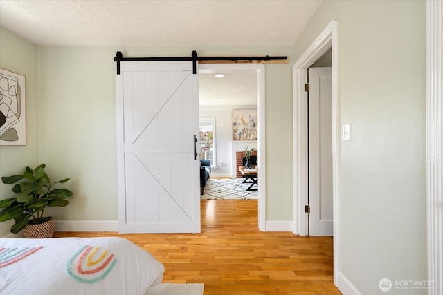 7530 25th Ave NW, Seattle, WA 98117 - bedroom with a textured ceiling, light wood-type flooring, baseboards, a barn door, and recessed lighting