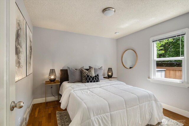7530 25th Ave NW, Seattle, WA 98117 - bedroom with baseboards, a textured ceiling, and wood finished floors