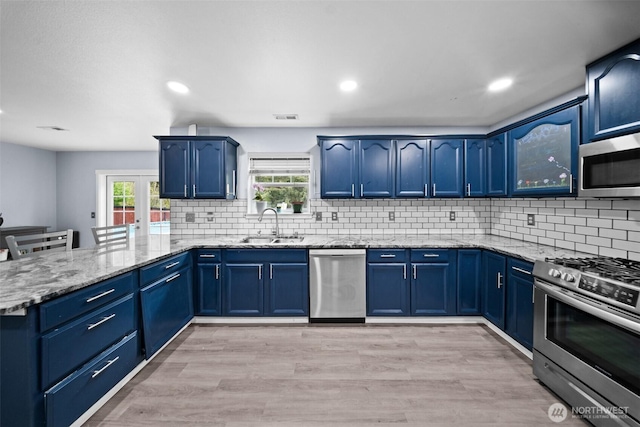 20723 197th Ave E, Orting, WA 98360 - kitchen with appliances with stainless steel finishes, a peninsula, light stone countertops, blue cabinetry, and recessed lighting