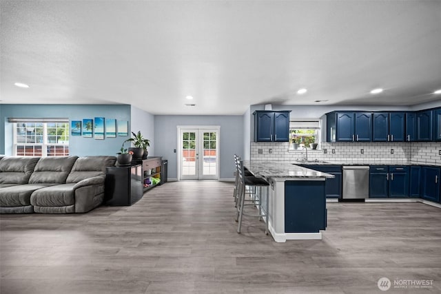 20723 197th Ave E, Orting, WA 98360 - kitchen with blue cabinets, dishwasher, a kitchen bar, light wood-style floors, and healthy amount of natural light