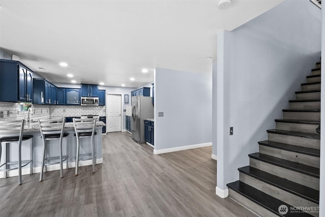 20723 197th Ave E, Orting, WA 98360 - kitchen featuring blue cabinets, stainless steel appliances, a peninsula, tasteful backsplash, and baseboards