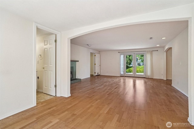 11112 E Riverside Dr, Bothell, WA 98011 - unfurnished room featuring a brick fireplace, arched walkways, light wood-type flooring, baseboards, and recessed lighting