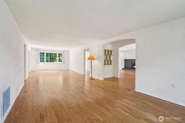11112 E Riverside Dr, Bothell, WA 98011 - unfurnished living room featuring arched walkways, wood finished floors, a fireplace, and baseboards