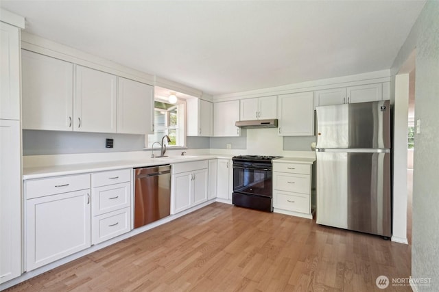 11112 E Riverside Dr, Bothell, WA 98011 - kitchen with stainless steel appliances, a sink, under cabinet range hood, white cabinetry, and light wood-style floors