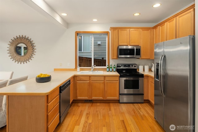 7522 NE 204th Pl, Kenmore, WA 98028 - kitchen featuring appliances with stainless steel finishes, a peninsula, a sink, light wood-style floors, and recessed lighting