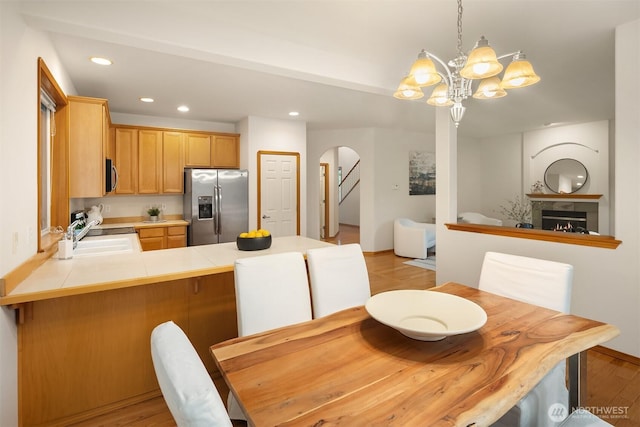 7522 NE 204th Pl, Kenmore, WA 98028 - dining space featuring arched walkways, a chandelier, recessed lighting, light wood finished floors, and a warm lit fireplace