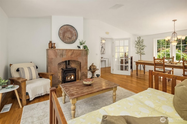 11002 Hyla Ave NE, Bainbridge Island, WA 98110 - living area featuring wood finished floors, vaulted ceiling, a chandelier, a wood stove, and baseboards