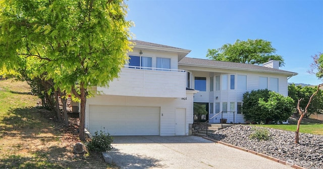 301 Canyon Pl, Wenatchee, WA 98801 - view of front of home with driveway, a balcony, a garage, and a chimney