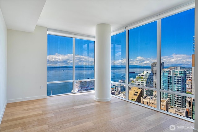 121 Stewart St Unit 2507, Seattle, WA 98101 - empty room with floor to ceiling windows, wood finished floors, a city view, baseboards, and a water view
