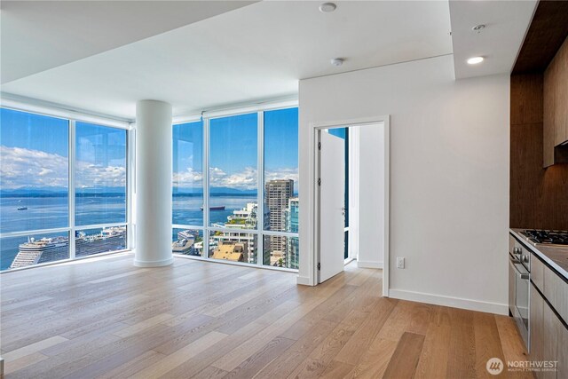 121 Stewart St Unit 2507, Seattle, WA 98101 - spare room featuring a wall of windows, light wood-type flooring, baseboards, a water view, and a smoke detector
