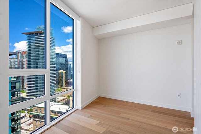 121 Stewart St Unit 2507, Seattle, WA 98101 - unfurnished room with wood finished floors, a city view, and baseboards