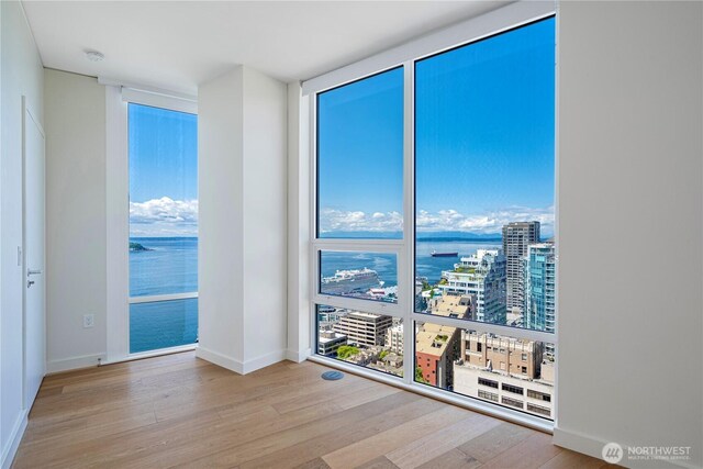 121 Stewart St Unit 2507, Seattle, WA 98101 - spare room with wood finished floors, healthy amount of natural light, baseboards, and a city view