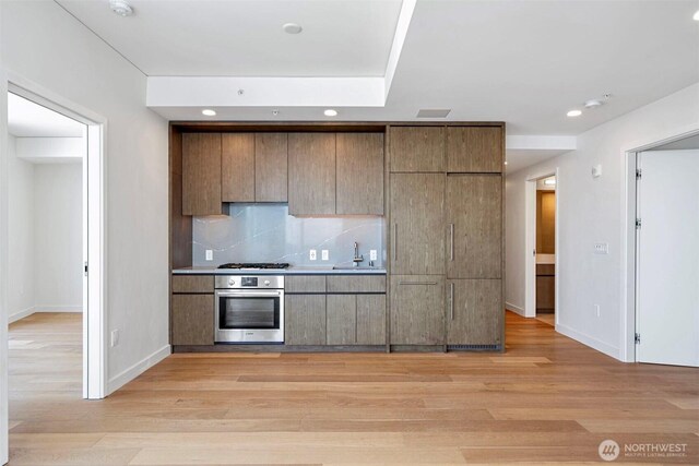 121 Stewart St Unit 2507, Seattle, WA 98101 - kitchen with oven, a sink, gas stovetop, decorative backsplash, and recessed lighting