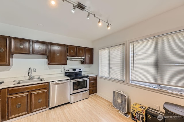 12304 NE 147th Ct, Kirkland, WA 98034 - kitchen featuring stainless steel appliances, under cabinet range hood, a sink, rail lighting, and light wood finished floors