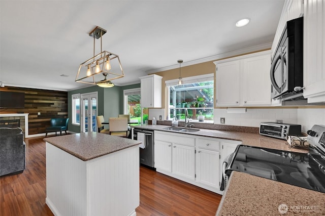24213 41st Ave E, Spanaway, WA 98387 - kitchen featuring stainless steel appliances, white cabinets, a kitchen island, a sink, and wood walls