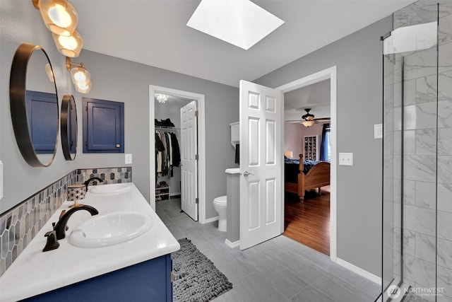 24213 41st Ave E, Spanaway, WA 98387 - ensuite bathroom featuring toilet, a stall shower, double vanity, baseboards, and a skylight