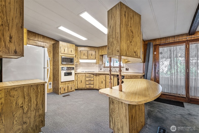 7300 32nd Ave NE Unit 5, Olympia, WA 98516 - kitchen featuring white oven, dark carpet, stainless steel microwave, under cabinet range hood, and wooden walls