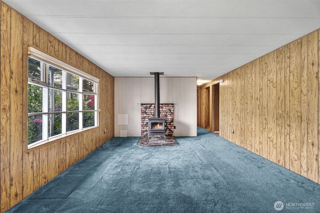 7300 32nd Ave NE Unit 5, Olympia, WA 98516 - unfurnished living room featuring carpet floors, a wood stove, and wood walls