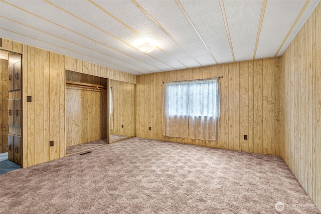 7300 32nd Ave NE Unit 5, Olympia, WA 98516 - unfurnished bedroom featuring carpet flooring, wooden walls, a closet, and a textured ceiling